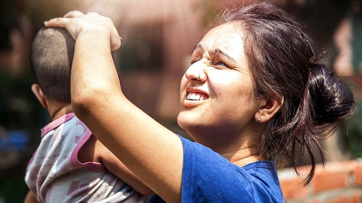 दिल्ली की गर्मी में चिलचिलाती धूप से अपने बच्चे को बचाती मां. गर्मियों को हीट स्ट्रोक के मामले भी बढ़ जाते हैं. (File Photo: Getty)