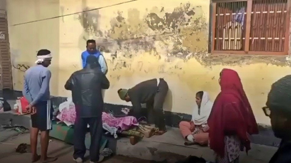 उन्नाव में मकान से निकाले जाने के बाद पति के शव के साथ बाहर बैठी महिला (Photo- Screengrab)